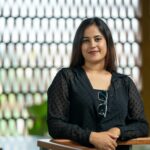 Smiling woman in a casual outfit poses confidently indoors.