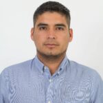 Portrait of a confident man in a blue shirt against a white background.