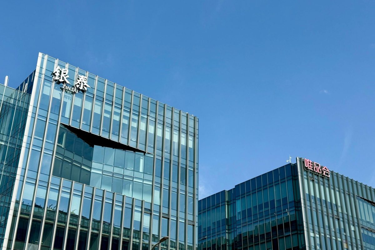 Close-up of modern glass facade buildings under a clear blue sky in Shanghai, China.